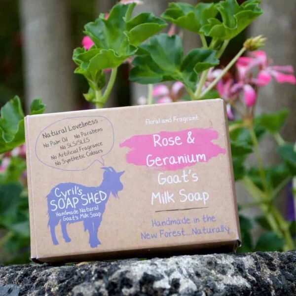 Rose and Geranium goats milk soap cardboard box leaning on a geranium pelargonium plant with pink flowers