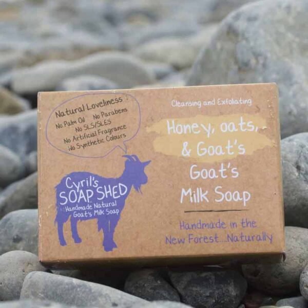 Honey, oats and goats milk soap brown cardboard box packaging with purple goat logo set on a grey pebble background