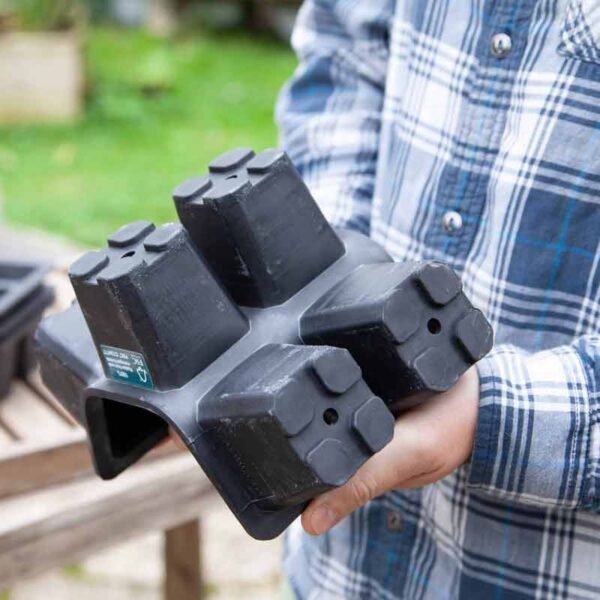 Plastic free rubber plant tray with 6 large cells being bent by a man to show it's flexibility