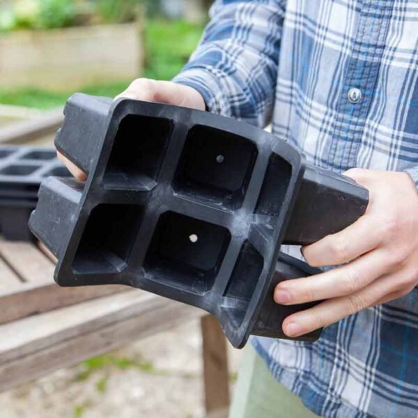 Plastic free rubber plant tray with 6 large cells being bent by a man to show it's flexibility