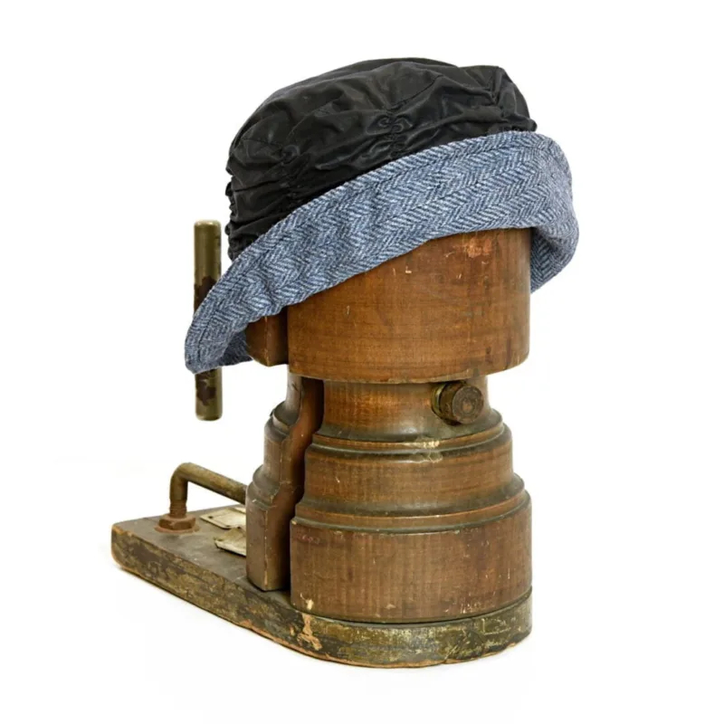 Navy ble cloche hat with a blue herringbone tweed brim on old wooden hat stretcher