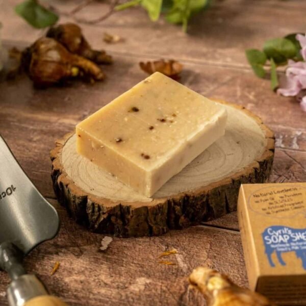 gardeners goats milk soap on a wood slices with scattered bulbs and a trowel