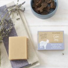 calm dog goats milk shampoo bar on a blue and while towel next to it's cardboard packaging