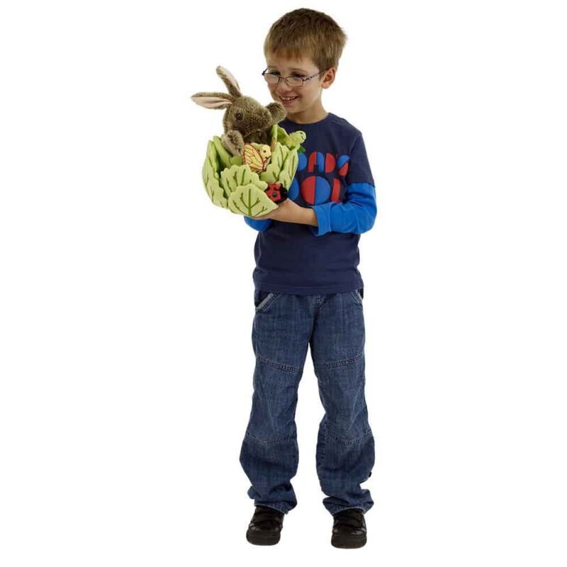 A young boy in blue, wearing glasses is holding the rabbit in lettuce hide away puppet with the ladybird and butterfly finger puppets ate tucked into the lettuce leaves