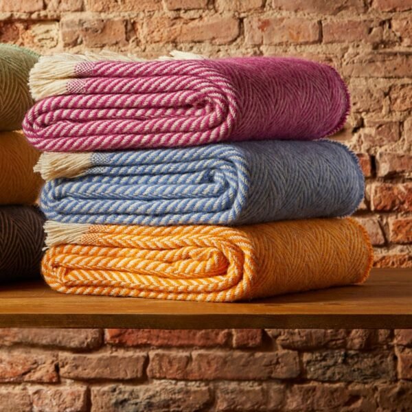 100% wool recycled throw 3 in a pile on a brick wall indoors