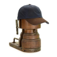 Tweedmill navy blue coloured wax baseball cap with dark brown leather brim on an old wooden hat form