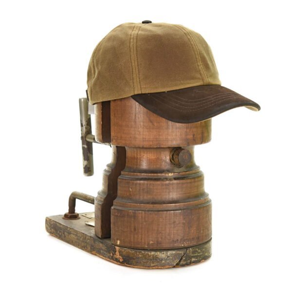 Tweedmill sand coloured wax baseball cap with dark brown leather brim on an old wooden hat form