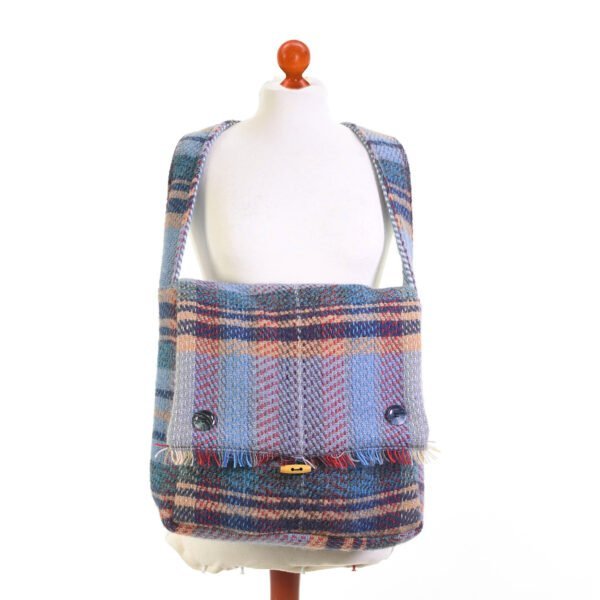 recycled wool bag in blues and reds showing the button details and toggle fastening around the neck of a cream mannequin