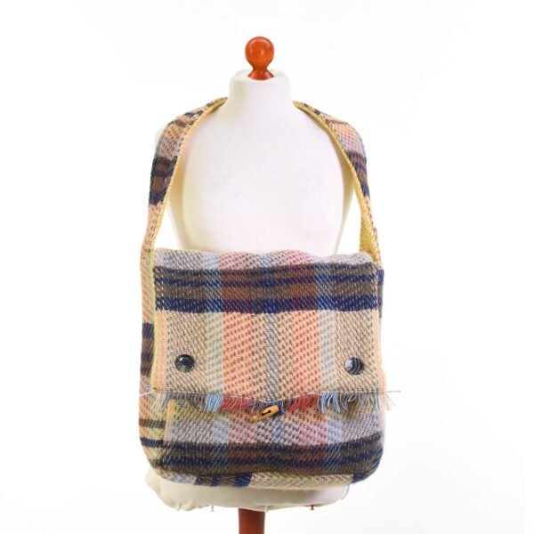 recycled wool bag in blues, beige and pinks showing the button details and toggle fastening around the neck of a cream mannequin