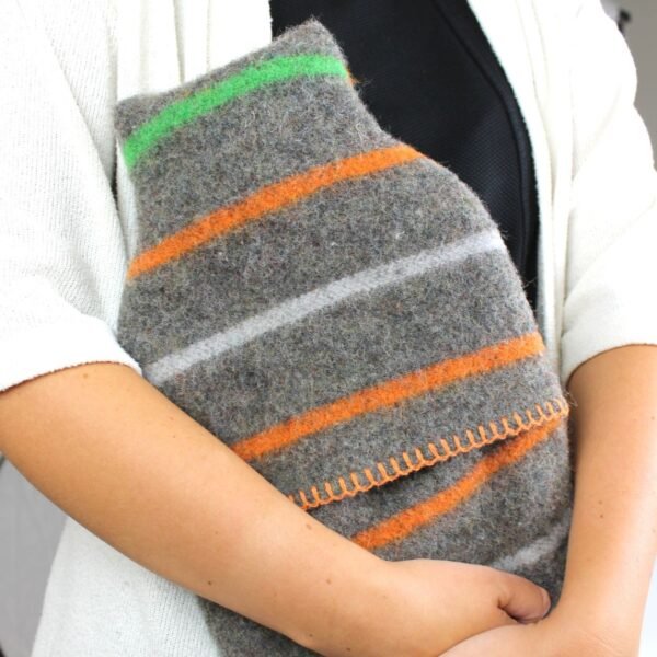 Tweedmill middle opening recycled wool hot water bottle and cover with grey background with orange, light grey and green stripes and orange thread blanket stitch