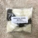 packet of white and brown nesting wool on a sheep fleece background