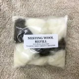 packet of white and brown nesting wool on a sheep fleece background