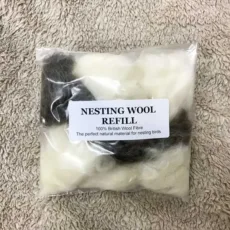 packet of white and brown nesting wool on a sheep fleece background