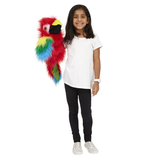 A young girl in a white t-shirt playing with the Red and Multi-coloured Amazon Macaw large hairy bird puppet on a white background