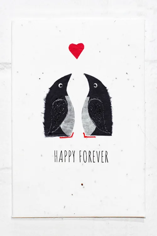 Two penguins below a heart with the text Happy Forever at the bottom on a textured plantable greeting card