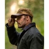 Male model facing right wearing the beige Brunswick Waxed Baseball Cap with leather brim in the outdoors