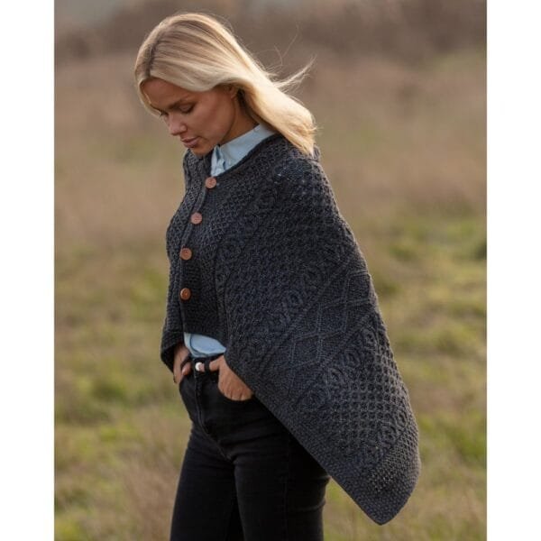 Female model wearing the iron grey 100% merino wool Remingtom Poncho in an Aran knit outside