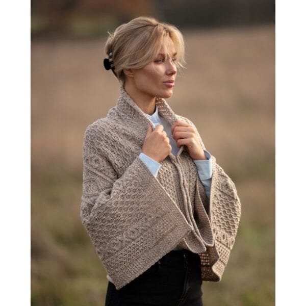 Female model wearing the Muslin 100% merino wool Remingtom Poncho in an Aran knit outside