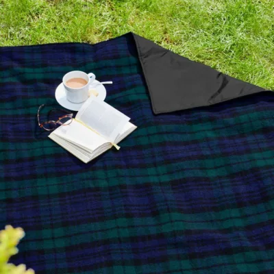 Blackwatch eventer rug with a cup of tea and an open book and top right corner turned to sho the black waterproof backing